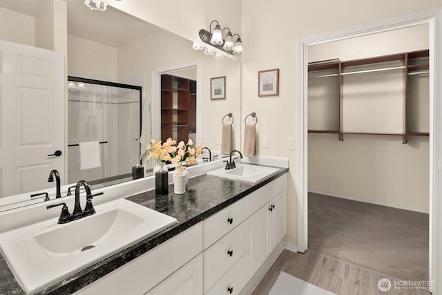 412 228th St SW Unit F101, Bothell, WA 98021 - full bathroom featuring double vanity, wood finished floors, a walk in closet, and a shower with door