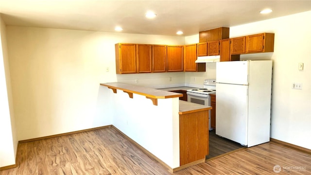 2316 Xenia St Unit 2316, Bellingham, WA 98229 - kitchen featuring white appliances, under cabinet range hood, a peninsula, brown cabinets, and light countertops