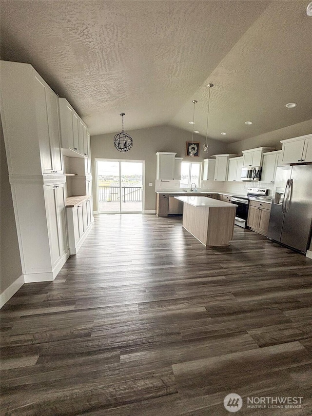 1522 E Marilyn Cir, Deer Park, WA 99006 - kitchen with appliances with stainless steel finishes, dark wood-style floors, lofted ceiling, a kitchen island, and a textured ceiling