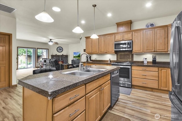15203 148th Avenue Ct E, Orting, WA 98360 - kitchen featuring appliances with stainless steel finishes, dark countertops, a ceiling fan, a warm lit fireplace, and recessed lighting