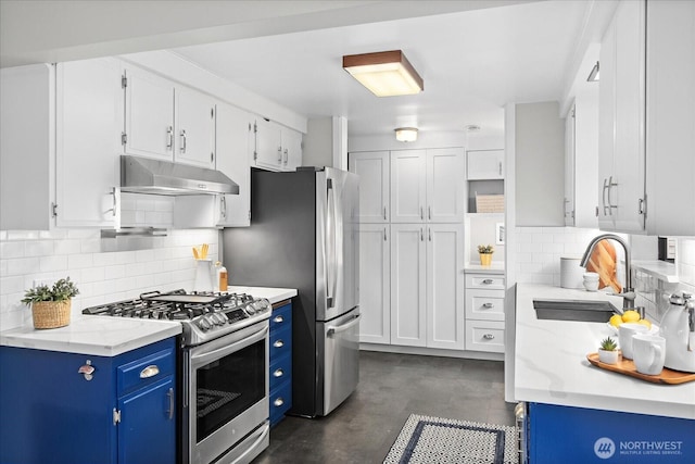 4301 1st Ave NW, Seattle, WA 98107 - kitchen featuring stainless steel appliances, blue cabinetry, under cabinet range hood, concrete floors, and decorative backsplash