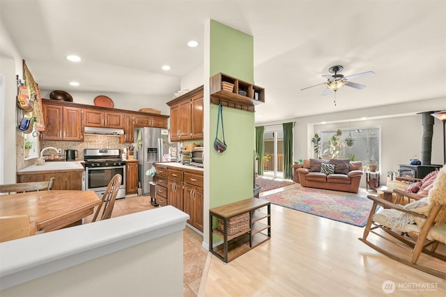 10 Cedar Pl, Bellingham, WA 98229 - kitchen featuring appliances with stainless steel finishes, under cabinet range hood, a wood stove, ceiling fan, and tasteful backsplash