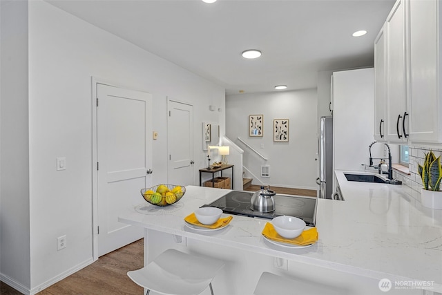 4802 Delridge Way SW, Seattle, WA 98106 - kitchen with black electric stovetop, freestanding refrigerator, white cabinets, wood finished floors, and recessed lighting