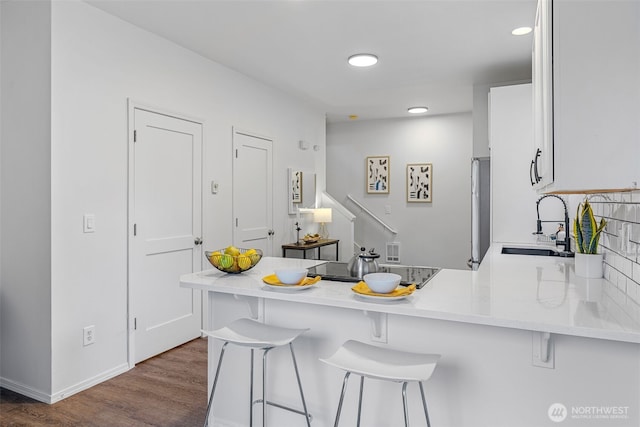 4802 Delridge Way SW, Seattle, WA 98106 - kitchen with a peninsula, a breakfast bar area, dark wood-type flooring, recessed lighting, and white cabinets