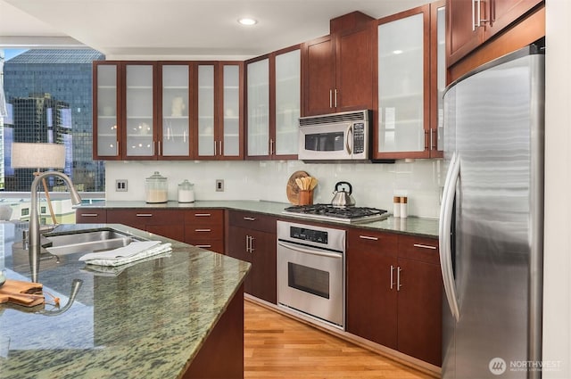 2033 2nd Ave Unit 703, Seattle, WA 98121 - kitchen featuring appliances with stainless steel finishes, glass insert cabinets, light wood-type flooring, dark stone countertops, and recessed lighting