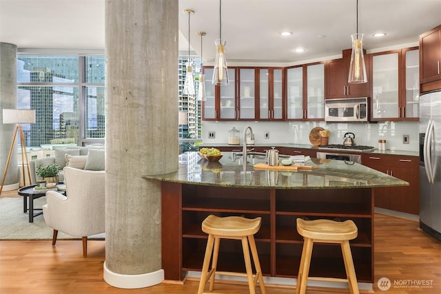 2033 2nd Ave Unit 703, Seattle, WA 98121 - kitchen featuring stainless steel appliances, light wood-type flooring, glass insert cabinets, a kitchen breakfast bar, and recessed lighting