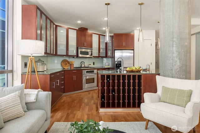 2033 2nd Ave Unit 703, Seattle, WA 98121 - kitchen with appliances with stainless steel finishes, light wood finished floors, dark countertops, open floor plan, and pendant lighting