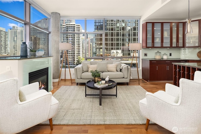 2033 2nd Ave Unit 703, Seattle, WA 98121 - living room featuring a city view, a wall of windows, wood finished floors, and a glass covered fireplace