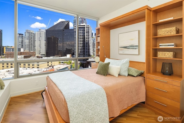 2033 2nd Ave Unit 703, Seattle, WA 98121 - bedroom featuring wood finished floors, a skyline view, floor to ceiling windows, and multiple windows
