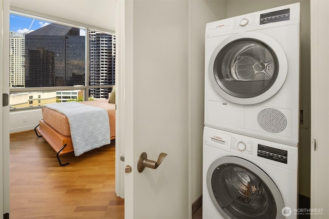 2033 2nd Ave Unit 703, Seattle, WA 98121 - washroom featuring stacked washer / dryer and wood finished floors