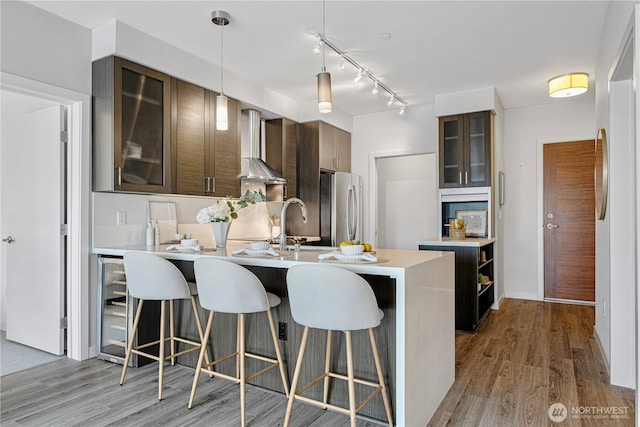 1760 NW 56th St Unit 520, Seattle, WA 98107 - kitchen with freestanding refrigerator, wall chimney exhaust hood, wine cooler, a kitchen bar, and light countertops