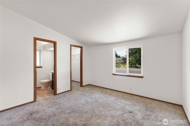 12407 Prairie Ridge Dr E, Bonney Lake, WA 98391 - unfurnished bedroom featuring carpet flooring, a walk in closet, a closet, vaulted ceiling, and ensuite bathroom