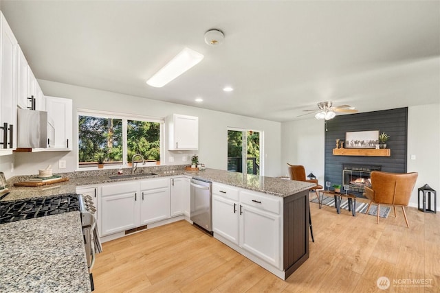 2141 Jason Ct, Ferndale, WA 98248 - kitchen with appliances with stainless steel finishes, light wood-type flooring, a large fireplace, white cabinetry, and a peninsula