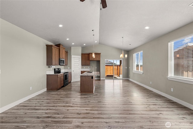 832 Q St SW, Quincy, WA 98848 - kitchen featuring stainless steel appliances, open floor plan, vaulted ceiling, wood finished floors, and an island with sink
