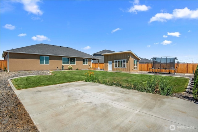 832 Q St SW, Quincy, WA 98848 - rear view of house with a trampoline, a patio, a fenced backyard, board and batten siding, and an outdoor structure