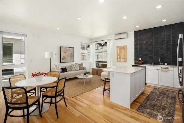 6042B 41st Ave SW, Seattle, WA 98136 - kitchen with light wood finished floors, a wall unit AC, white cabinets, light countertops, and a kitchen bar