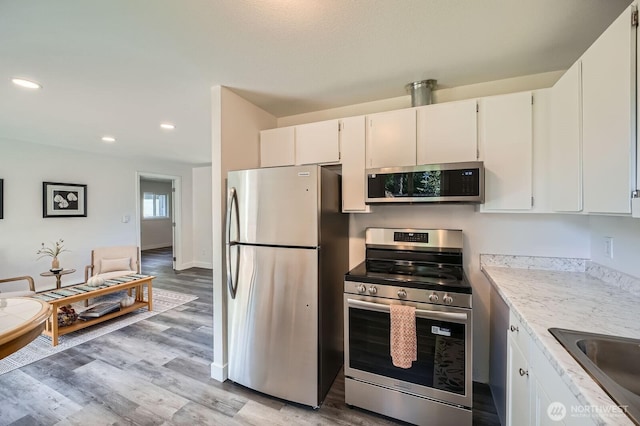 10985 SE 225th St, Kent, WA 98031 - kitchen with appliances with stainless steel finishes, light wood finished floors, recessed lighting, and white cabinetry