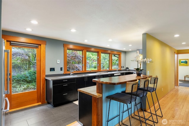 1201 Wilson St, Port Townsend, WA 98368 - kitchen with dark cabinets, butcher block countertops, a kitchen breakfast bar, recessed lighting, and light wood-style flooring