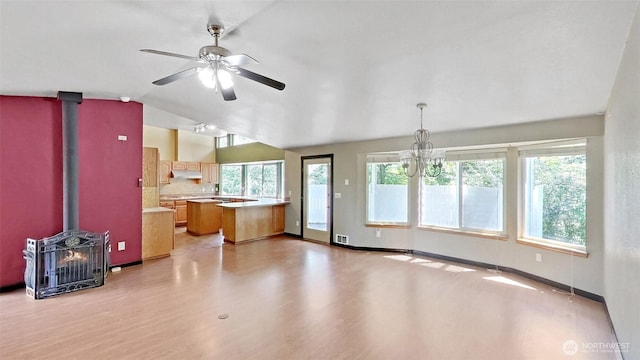 24250 164th Ave SE, Kent, WA 98042 - unfurnished living room featuring lofted ceiling, a wood stove, healthy amount of natural light, a chandelier, and light wood-style floors