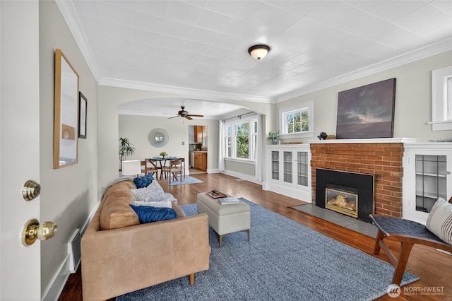 2318 F St, Bellingham, WA 98225 - living room featuring ornamental molding, ceiling fan, wood finished floors, a brick fireplace, and arched walkways