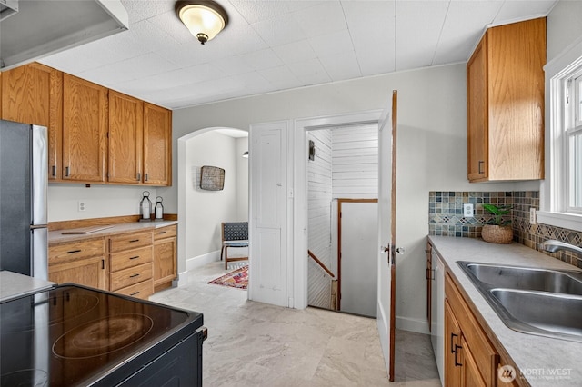 2318 F St, Bellingham, WA 98225 - kitchen with freestanding refrigerator, black electric range, arched walkways, decorative backsplash, and brown cabinets