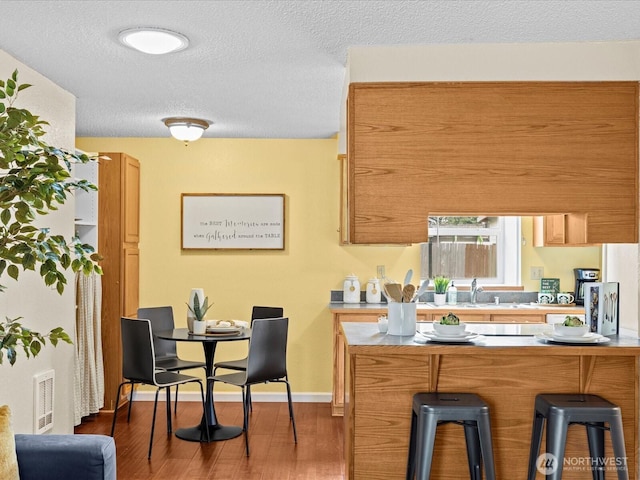 4811 76th St NE Unit 5, Marysville, WA 98270 - kitchen featuring a kitchen bar, wood finished floors, light countertops, a textured ceiling, and brown cabinetry