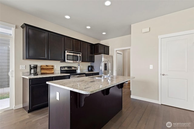 329 Holland Ave, Bellingham, WA 98226 - kitchen with stainless steel appliances, a breakfast bar area, dark wood-style flooring, a kitchen island with sink, and light stone countertops