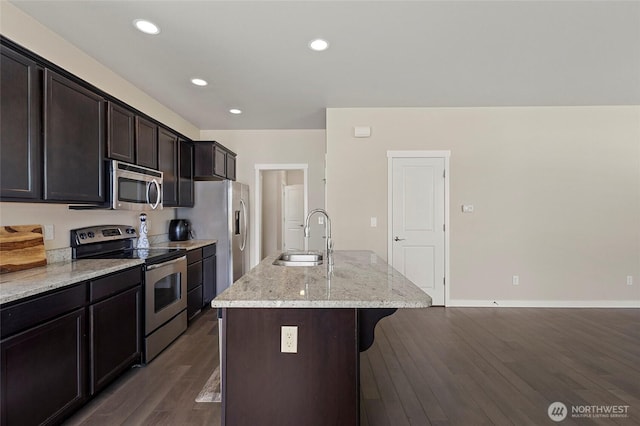 329 Holland Ave, Bellingham, WA 98226 - kitchen with stainless steel appliances, a breakfast bar area, dark wood-style flooring, a center island with sink, and light stone counters