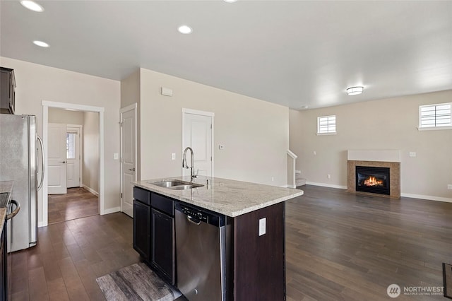 329 Holland Ave, Bellingham, WA 98226 - kitchen with appliances with stainless steel finishes, dark wood-type flooring, a kitchen island with sink, a glass covered fireplace, and light stone counters