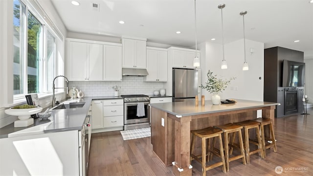 9608 NE 182nd Ct Unit D, Bothell, WA 98011 - kitchen with appliances with stainless steel finishes, under cabinet range hood, decorative backsplash, a center island, and dark wood-style flooring
