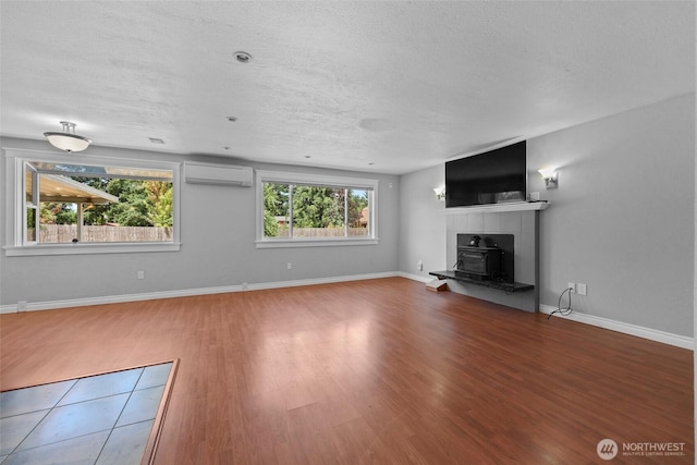 11636 25th Ave SE, Olympia, WA 98513 - unfurnished living room with an AC wall unit, wood finished floors, plenty of natural light, and a textured ceiling