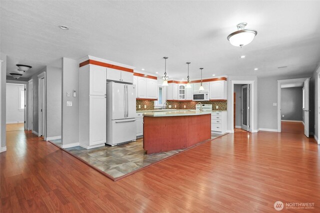 11636 25th Ave SE, Olympia, WA 98513 - kitchen with white appliances, a center island, white cabinets, wood finished floors, and recessed lighting