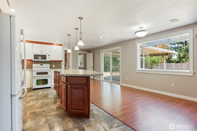 11636 25th Ave SE, Olympia, WA 98513 - kitchen with white appliances, light countertops, tasteful backsplash, an island with sink, and hanging light fixtures
