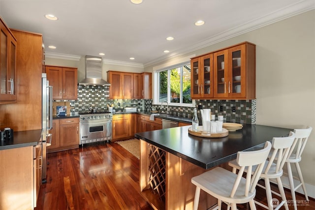 2542 12th Ave W, Seattle, WA 98119 - kitchen with wall chimney range hood, appliances with stainless steel finishes, a peninsula, brown cabinets, and ornamental molding