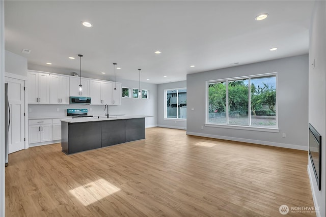 608B Deeded Ln SW, Orting, WA 98360 - kitchen with stainless steel microwave, range with electric stovetop, white cabinetry, light countertops, and recessed lighting