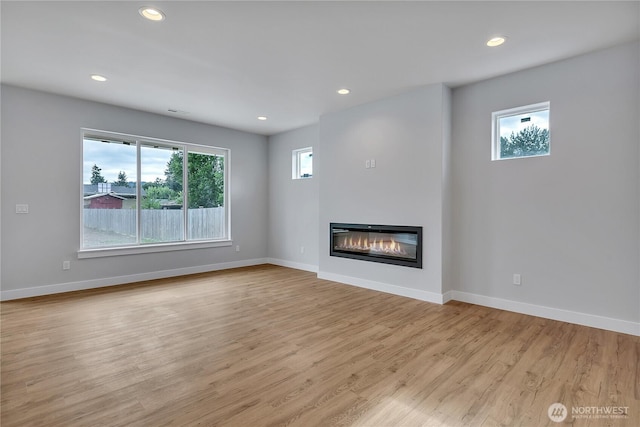 608B Deeded Ln SW, Orting, WA 98360 - unfurnished living room featuring light wood-style flooring, a glass covered fireplace, and recessed lighting