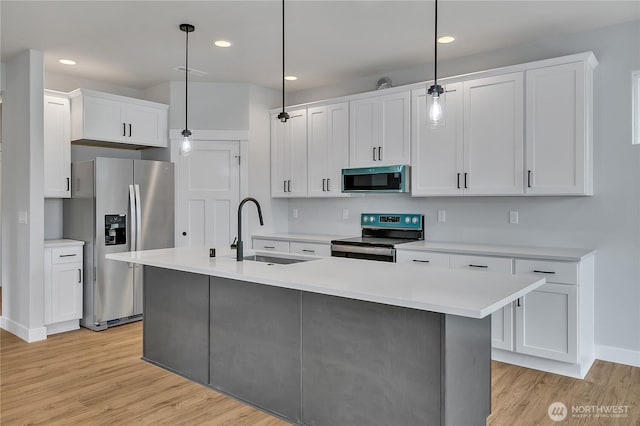 608B Deeded Ln SW, Orting, WA 98360 - kitchen with stainless steel appliances, light wood-style floors, light countertops, white cabinets, and decorative light fixtures
