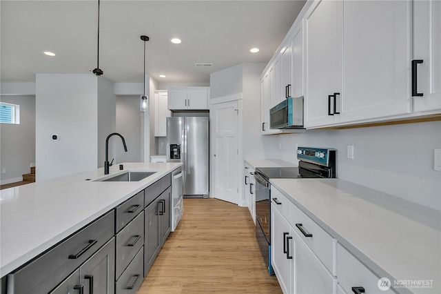 608B Deeded Ln SW, Orting, WA 98360 - kitchen with stainless steel appliances, light countertops, light wood-type flooring, hanging light fixtures, and white cabinets