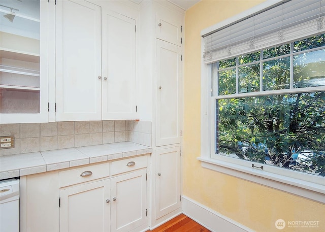 720 6th Ave Unit 206, Tacoma, WA 98405 - kitchen with white cabinets, tile countertops, white dishwasher, wood finished floors, and tasteful backsplash