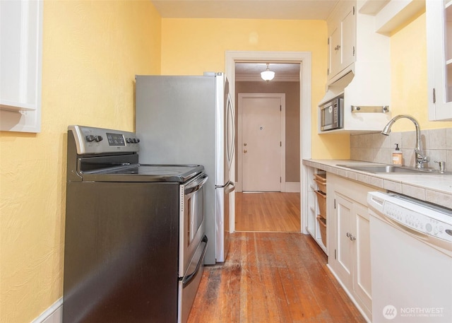 720 6th Ave Unit 206, Tacoma, WA 98405 - kitchen featuring stainless steel appliances, wood finished floors, white cabinets, tasteful backsplash, and light countertops