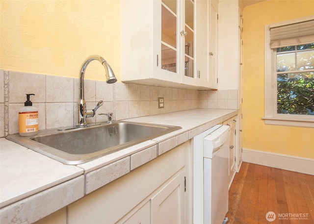 720 6th Ave Unit 206, Tacoma, WA 98405 - kitchen featuring white dishwasher, light wood-style flooring, white cabinets, glass insert cabinets, and decorative backsplash