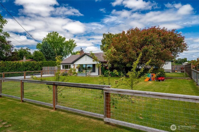 17371 Dunbar Rd, Mount Vernon, WA 98273 - view of front of home with a fenced backyard, a tiled roof, a chimney, and a playground