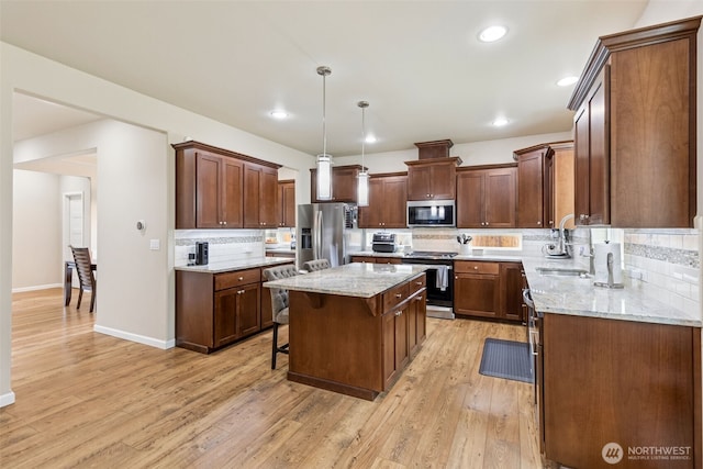 4921 Skylark St NE, Lacey, WA 98516 - kitchen with appliances with stainless steel finishes, tasteful backsplash, a kitchen island, light wood finished floors, and light stone counters