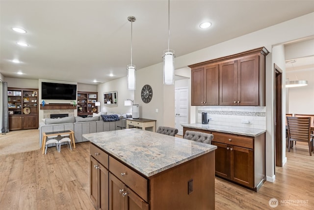 4921 Skylark St NE, Lacey, WA 98516 - kitchen featuring light wood-style floors, a kitchen island, tasteful backsplash, light stone countertops, and decorative light fixtures