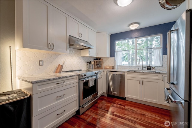 916 N 165th St Unit 7, Shoreline, WA 98133 - kitchen with appliances with stainless steel finishes, under cabinet range hood, dark wood finished floors, white cabinetry, and decorative backsplash