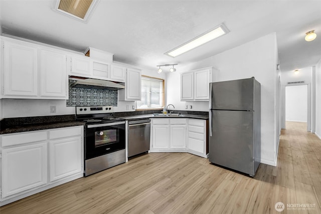 241B Foster Creek Rd, Toledo, WA 98591 - kitchen with stainless steel appliances, exhaust hood, white cabinetry, dark countertops, and light wood-style flooring