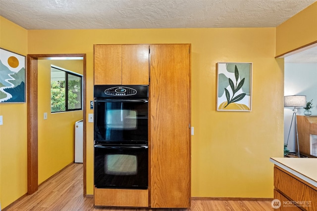 152 E Park Ln, Port Angeles, WA 98362 - kitchen featuring light wood-style flooring, a textured ceiling, light countertops, and brown cabinetry