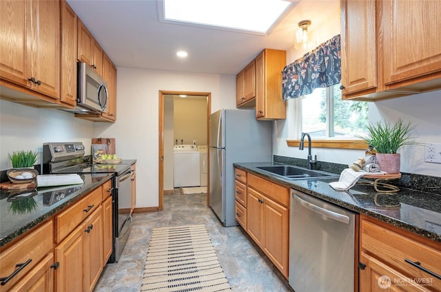 8618 94th St SW, Lakewood, WA 98498 - kitchen featuring stainless steel appliances, washer and dryer, a skylight, dark stone counters, and brown cabinets