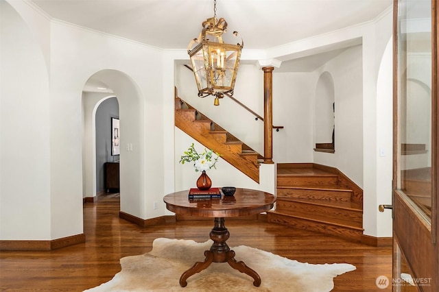 3103 Mount Rainier Dr S, Seattle, WA 98144 - foyer entrance with wood finished floors, stairs, arched walkways, a chandelier, and ornamental molding