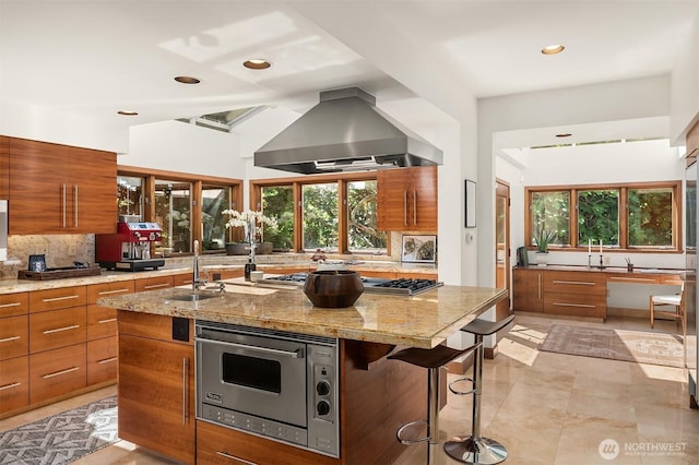 3103 Mount Rainier Dr S, Seattle, WA 98144 - kitchen with island exhaust hood, appliances with stainless steel finishes, brown cabinetry, modern cabinets, and decorative backsplash